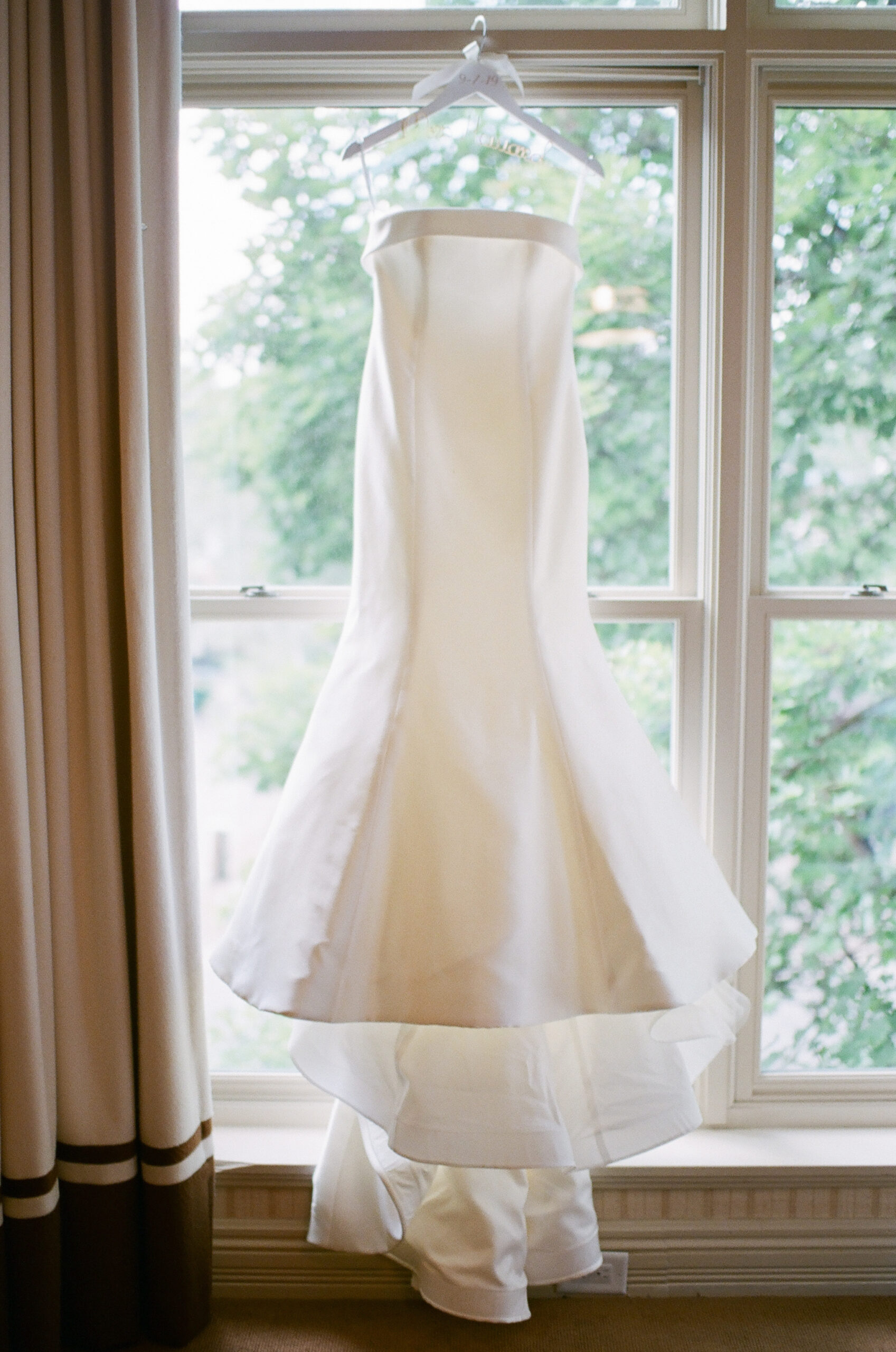 planning-a-destination-wedding-in-new-england the brides white gown hanging in the window