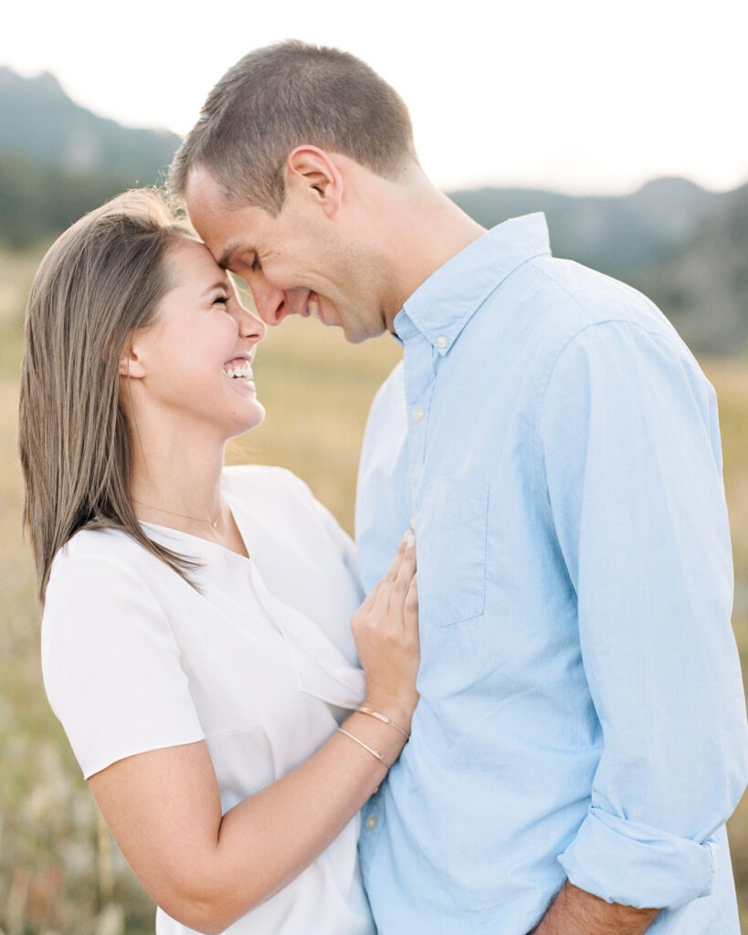 Smiling couple shares a tender moment during engagement session on romantic getaways in New England.