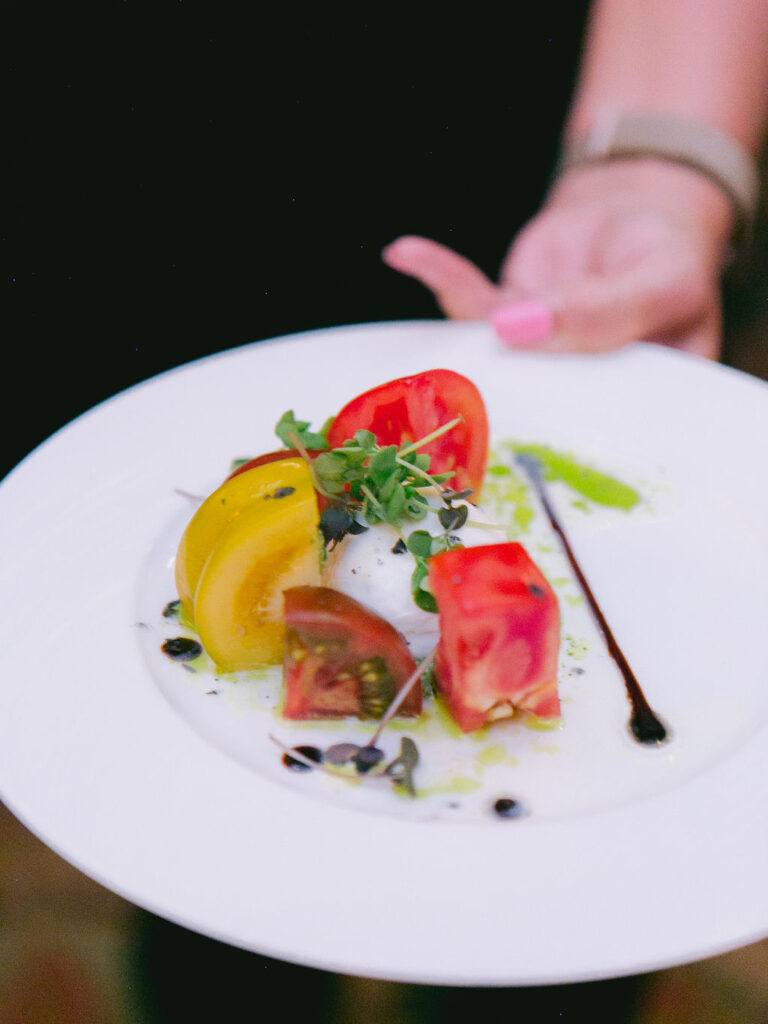 Colorful heirloom tomato salad served with microgreens, highlighting eco-friendly wedding tips for sustainable catering.