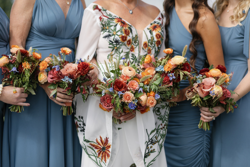 2026 wedding design trend with embroidered bridal gown and bold floral bouquets in rich fall tones.