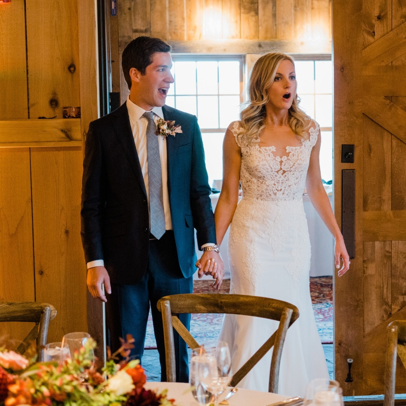 Bride and groom reacting with joy as they enter their warmly decorated wedding reception space.