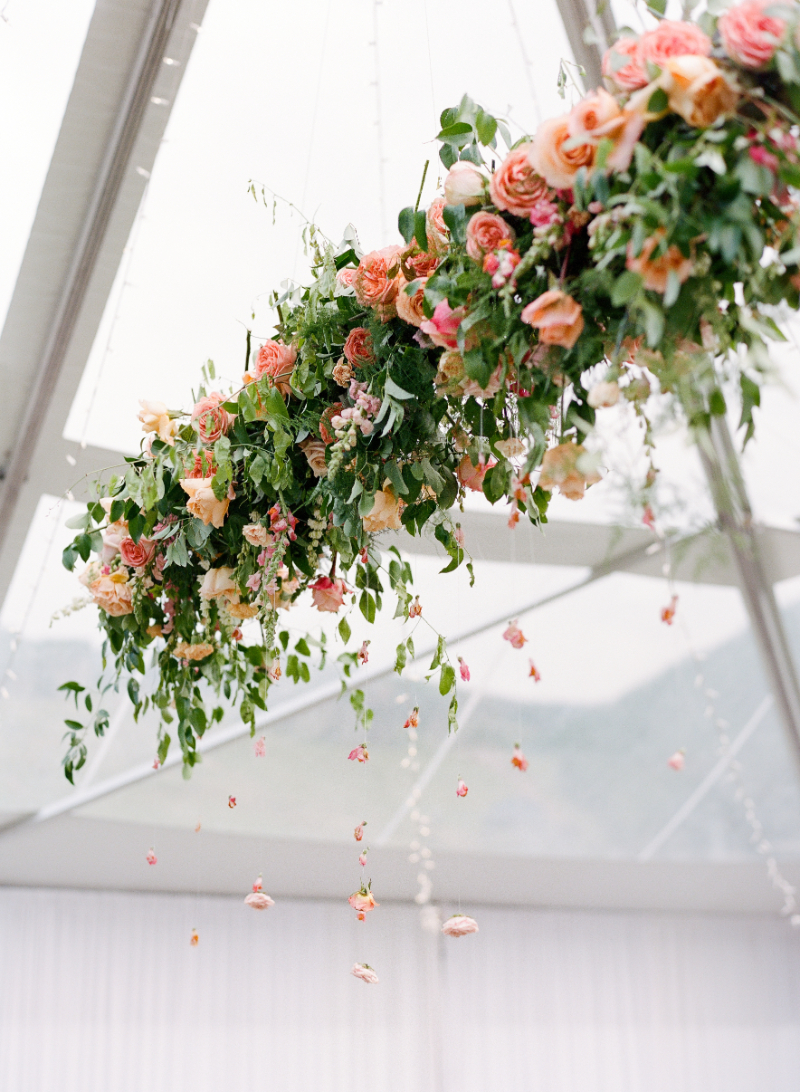 Floral ceiling installation designed by wedding planner featuring roses, greenery, and floating blooms.