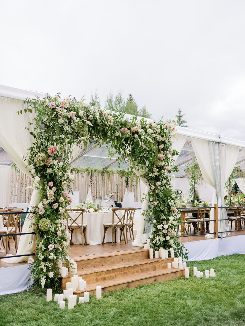 Floral arch with candles at reception entrance highlighting romantic, elevated wedding design ideas.