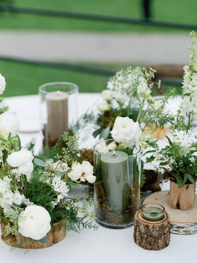 Woodsy centerpiece with white florals, green candles, and moss for organic wedding design ideas.