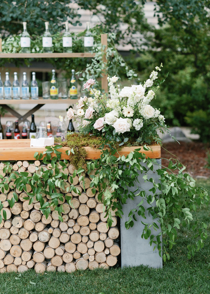 Wood and concrete bar with floral accents and greenery, offering organic cocktail hour wedding design ideas.