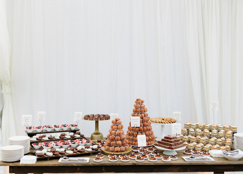 Elegant dessert table display with donut towers, cookies, brownies, and bite-sized treats for guests.