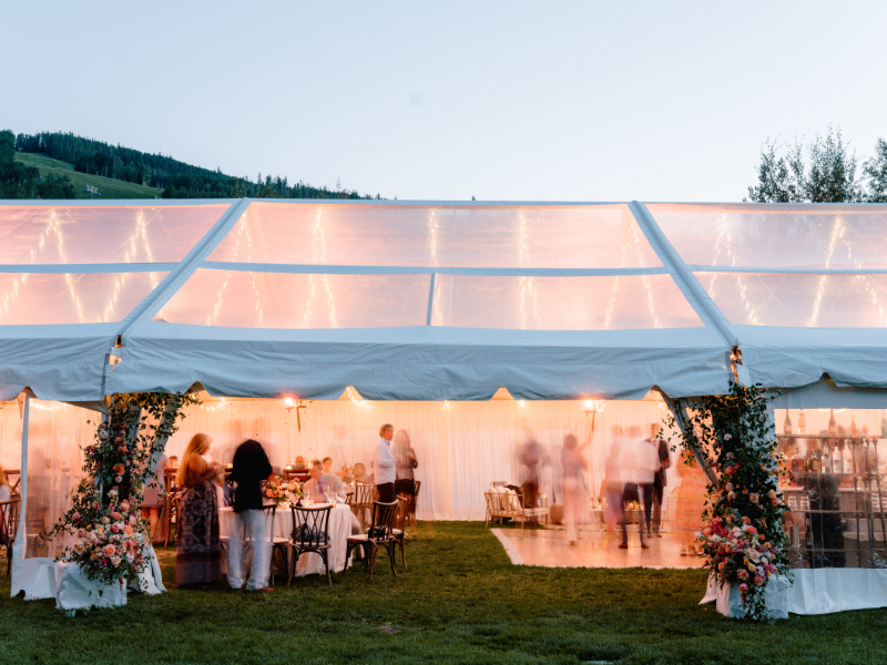 Evening tented reception glowing with lights and florals during mountain multi-day wedding experiences.