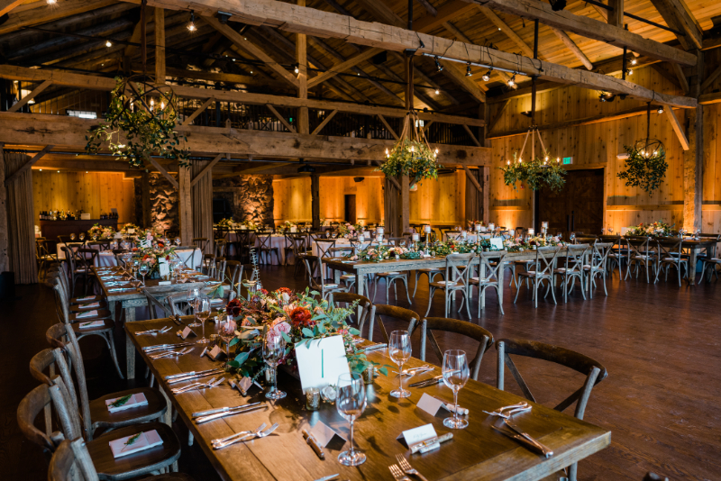 Rustic-elegant wedding reception setup with floral centerpieces.