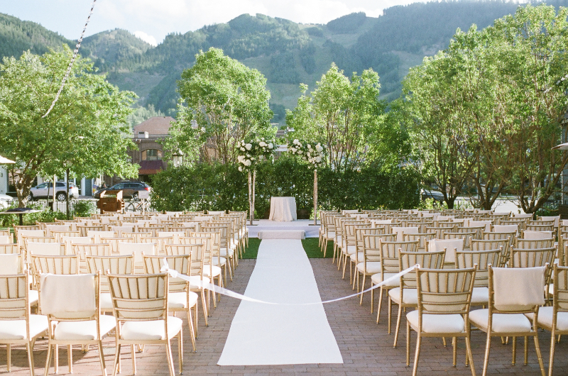 Mountain view ceremony setup with gold chairs and white florals for couples who just got engaged.