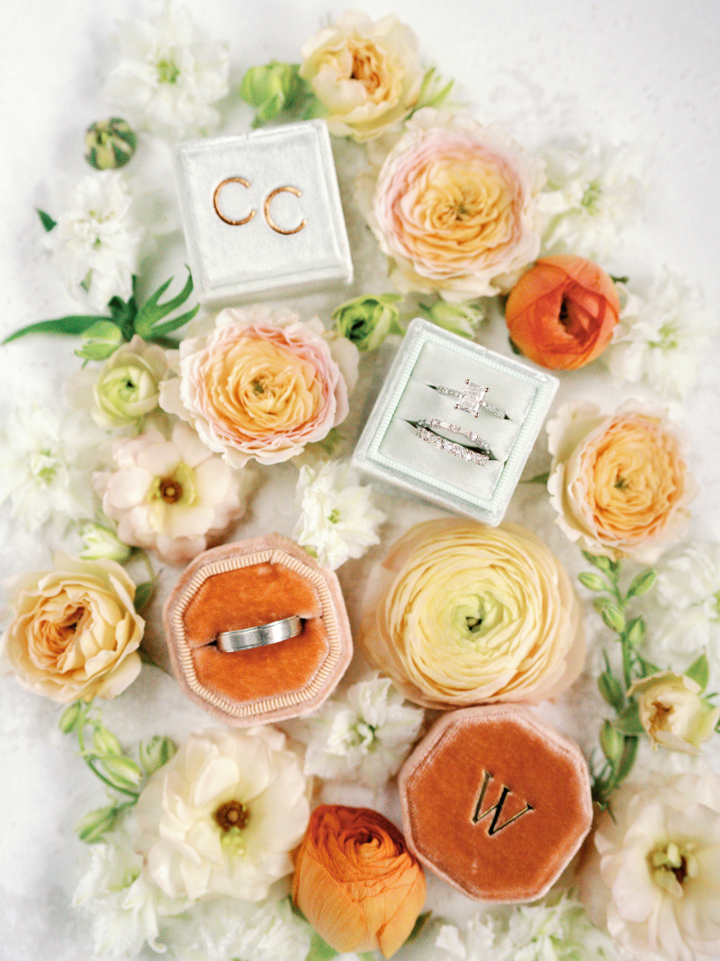 Flat lay of wedding rings and colorful florals, a joyful detail for couples who just got engaged.