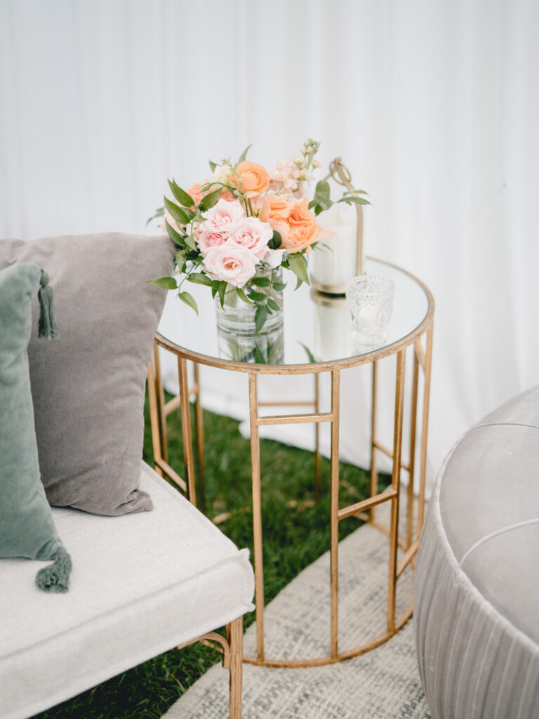 Elegant lounge vignette with gold side table, soft florals, and layered seating details.