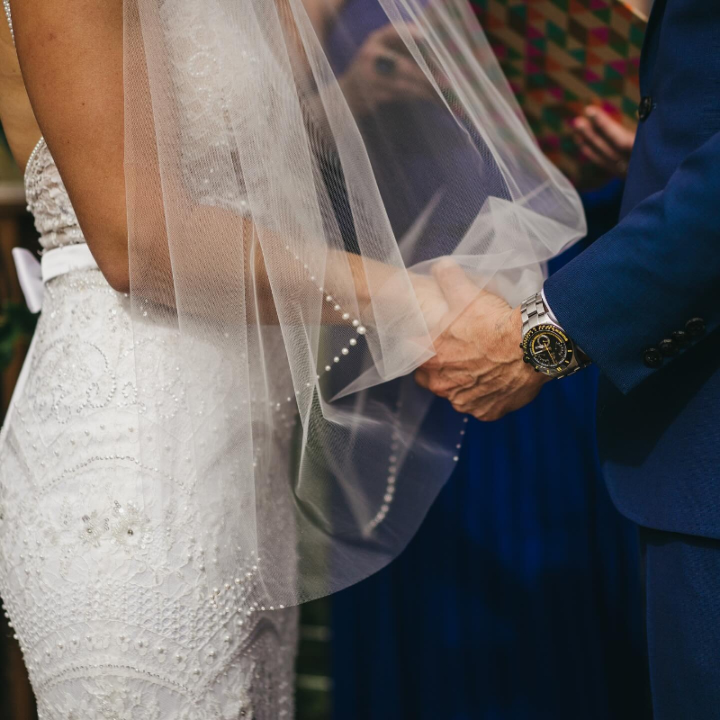 Boston wedding planner capturing intimate ceremony moment with bride and groom holding hands under veil