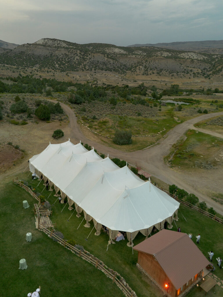 Large sailcloth tent set for a Colorado ranch wedding at Lazy J Ranch surrounded by open fields and mountain landscape.