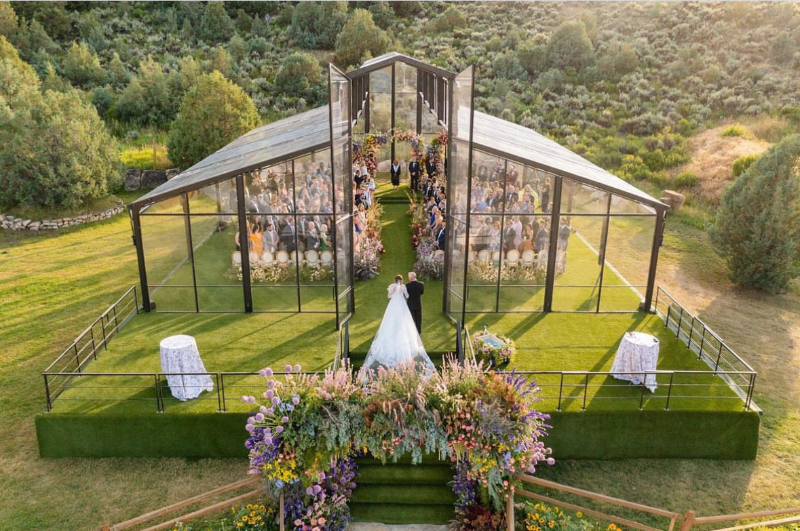 Outdoor ceremony at a Colorado ranch wedding at Lazy J Ranch with floral aisle and glass structure overlooking the mountains.