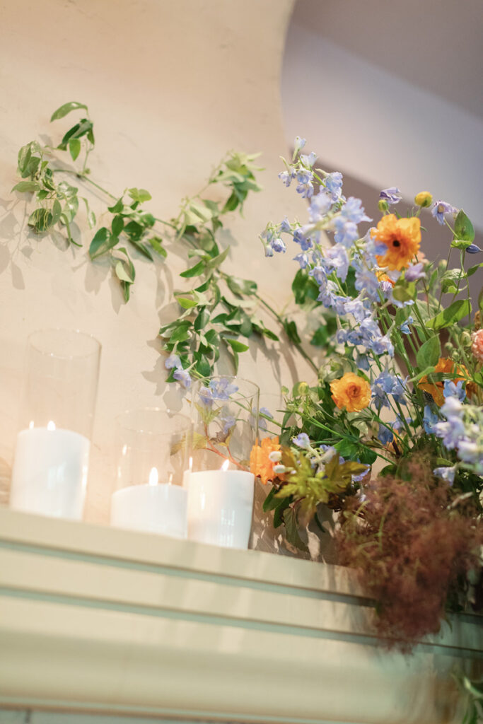 Soft candlelight with delicate florals in blue and peach arranged along a refined mantel display