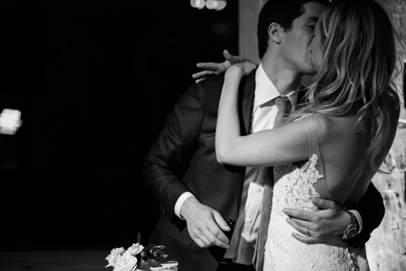 Romantic couple sharing a kiss during reception, elegant and intimate moment captured in soft evening light