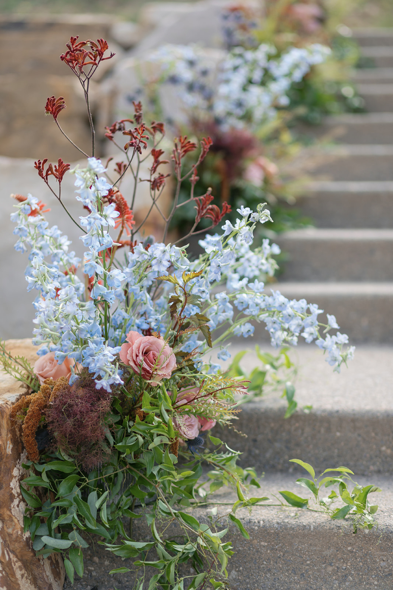 Romantic floral wedding design with soft blue delphinium and garden-inspired blooms beside elegant stone steps.