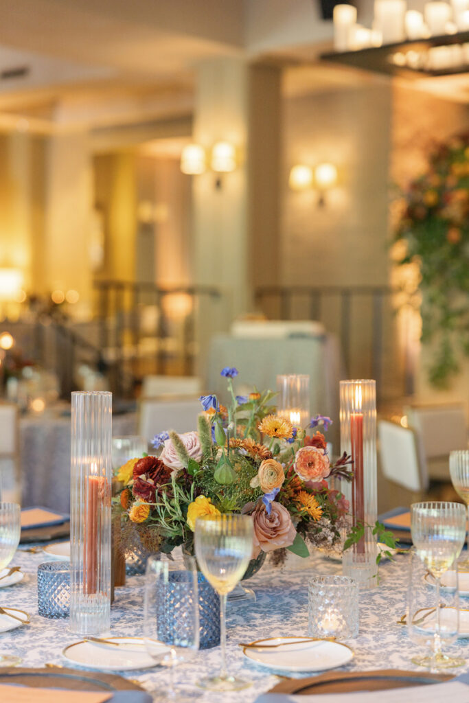 Elegant reception wedding design with colorful florals, layered candlelight, and patterned linens for a romantic atmosphere.