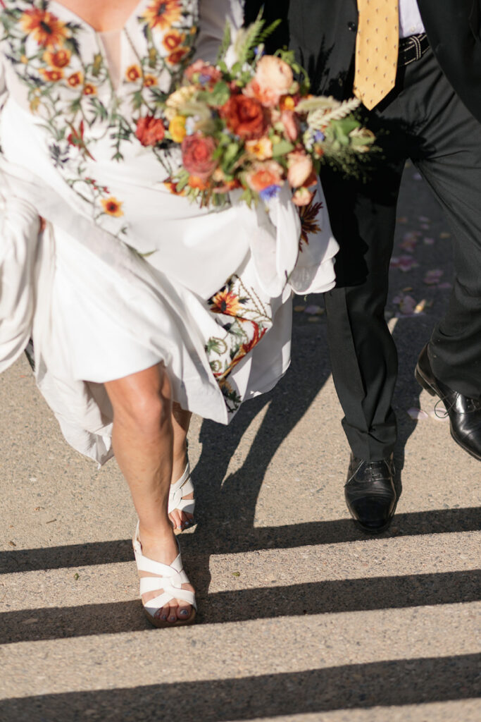 Colorful floral wedding design with embroidered bridal gown and warm autumn-inspired bouquet details outdoors.
