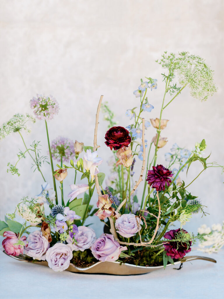 Colorful floral centerpiece with lavender roses and deep burgundy blooms, reflecting thoughtful luxury wedding logistics and design.